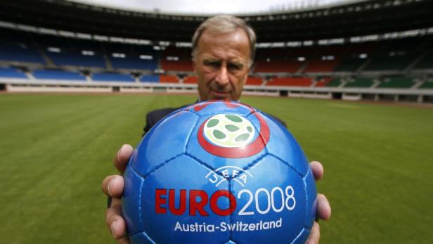 Ein Mann hält einen blauen Fußball der EURO 2008 Austria-Switzerland vor einem Stadion.