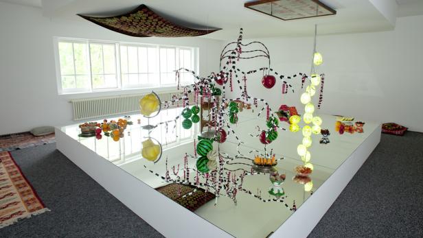 Eine Installation mit Obstmotiven und Spiegeln in einem hellen Raum.