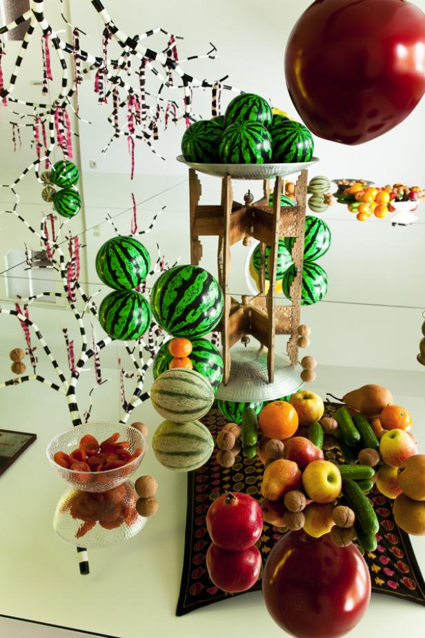 Ein Arrangement aus Obst und Gemüse, darunter Wassermelonen, Äpfel und Gurken.