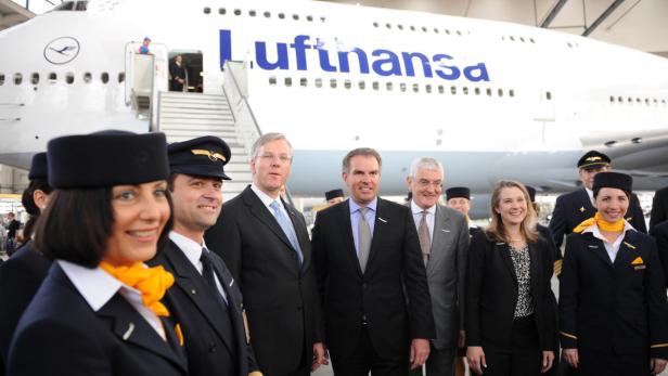 Eine Gruppe von Lufthansa-Mitarbeitern steht vor einem Lufthansa-Flugzeug.