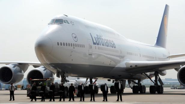 Eine Boeing 747 der Lufthansa steht auf dem Rollfeld, umgeben von Bodenpersonal und Musikern.