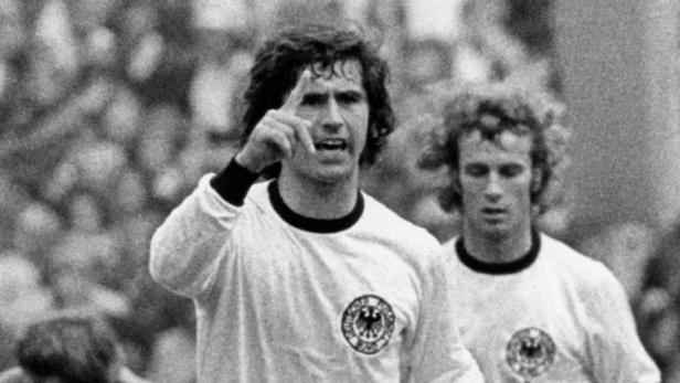 Franz Beckenbauer gestikuliert während eines Fußballspiels.