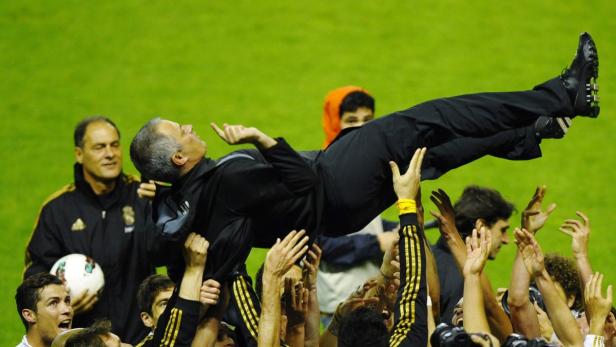 Fußballspieler feiern ihren Trainer, indem sie ihn in die Luft heben.