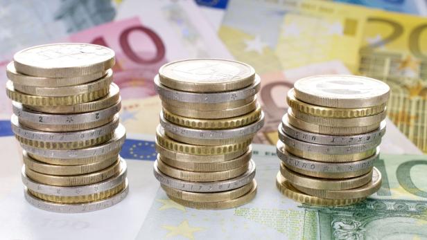 Drei Stapel von Euro-Münzen stehen auf Euro-Banknoten.