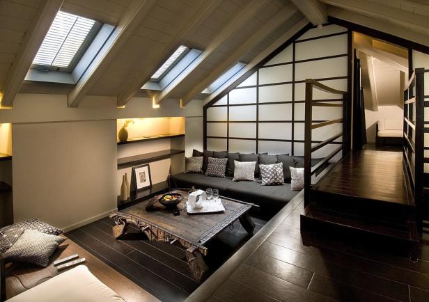 Ein gemütliches Dachzimmer mit Sofa, Tisch und Dachfenstern.