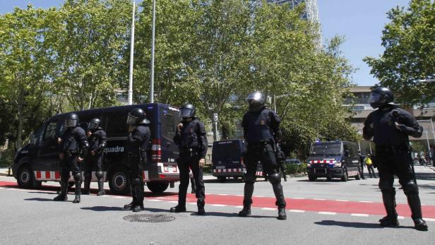 Eine Gruppe von Polizisten in Schutzausrüstung steht auf einer Straße in Barcelona.
