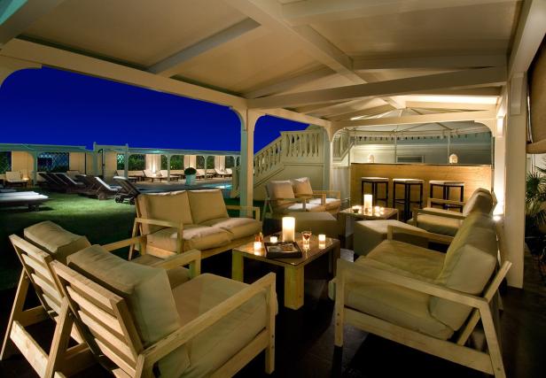 Ein abendlicher Außenbereich mit Lounge-Möbeln und Blick auf einen Pool.