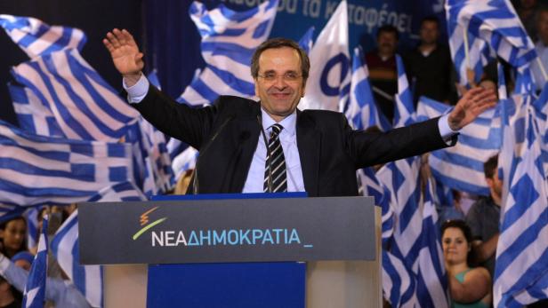 Antonis Samaras spricht vor einer Menge mit griechischen Flaggen.