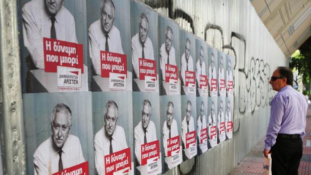 Ein Mann betrachtet Wahlplakate einer politischen Partei an einer Wand.