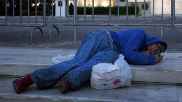Eine obdachlose Frau schläft im Freien auf einer Treppe.