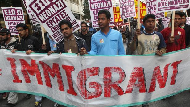 Eine Demonstration mit Menschen, die ein Transparent mit der Aufschrift „Immigrant“ tragen.