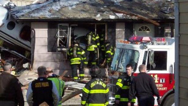 Ein Flugzeug ist in ein Haus gestürzt, Feuerwehrleute und Polizisten sind vor Ort.