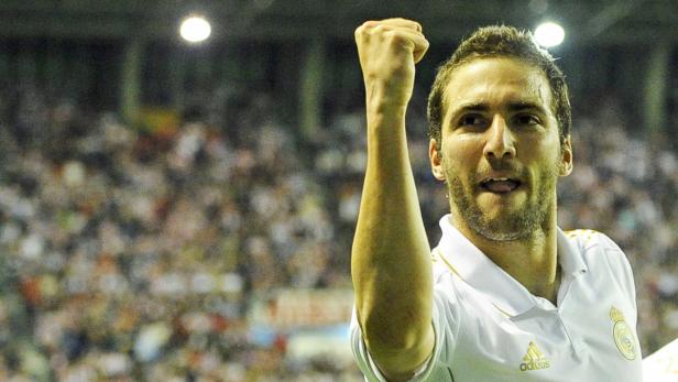 Ein Fußballspieler jubelt mit erhobener Faust vor einer Zuschauermenge.