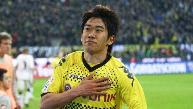 Shinji Kagawa im gelben Trikot von Borussia Dortmund mit der Hand auf der Brust.