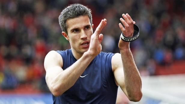 Robin van Persie klatscht mit einer Kapitänsbinde am Arm.
