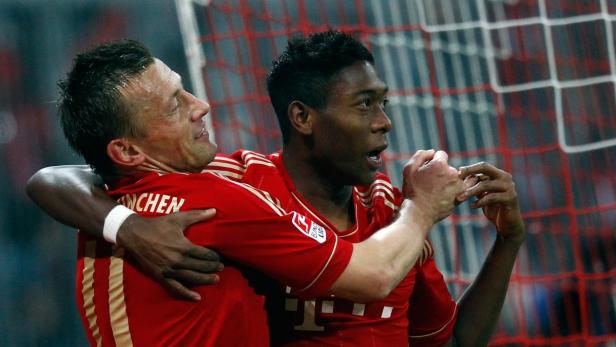 Zwei Fußballspieler des FC Bayern München umarmen sich auf dem Spielfeld.