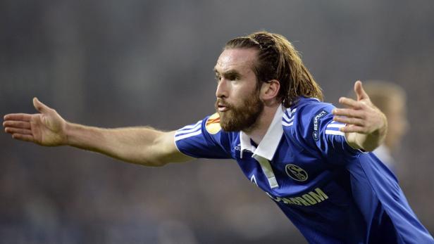 Ein Fußballspieler im blauen Trikot mit erhobenen Armen jubelt.