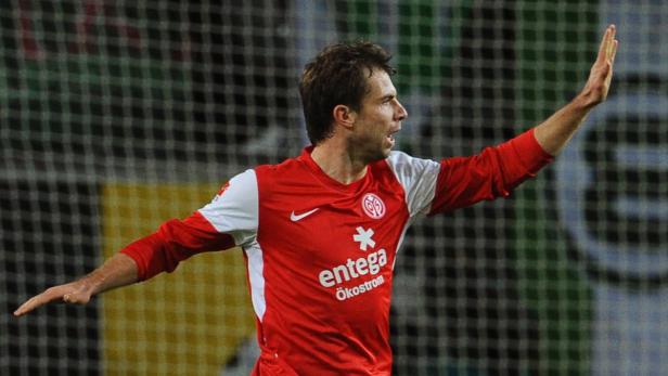 Ein Fußballspieler im roten Trikot streckt den Arm aus.