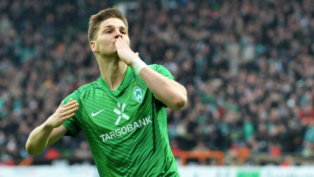Ein Fußballspieler im grünen Trikot von Werder Bremen küsst seine Hand.