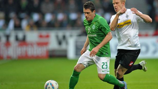 Ein Fußballspieler im grünen Trikot von Werder Bremen dribbelt den Ball.