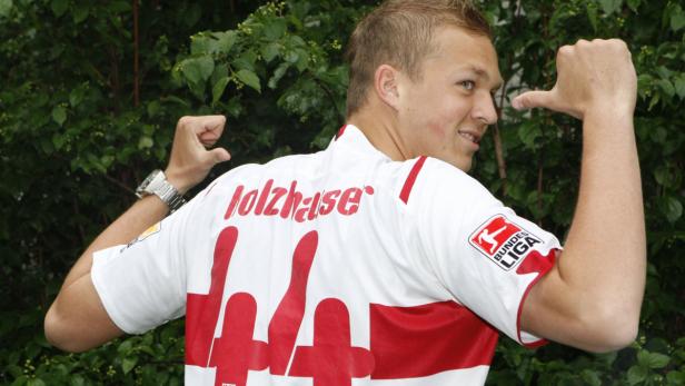 Ein Fußballspieler des VfB Stuttgart zeigt auf sein Trikot mit der Nummer 44 und dem Namen „Holzhauser“.