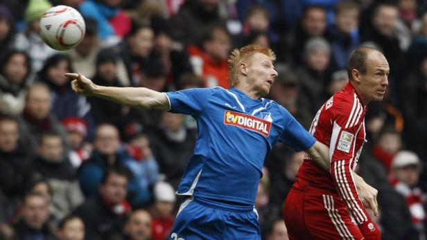 Zwei Fußballspieler kämpfen um den Ball vor einer Zuschauermenge.