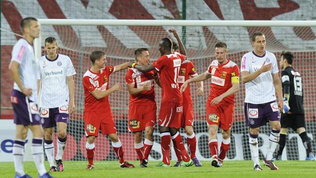Fußballspieler in roten Trikots feiern ein Tor.