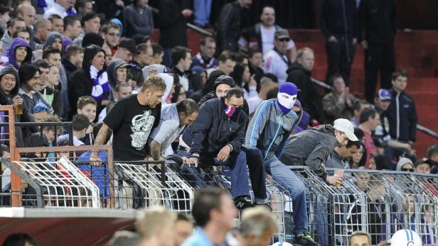 Eine Menschenmenge, darunter einige mit Sturmhauben, steht auf einer Tribüne.