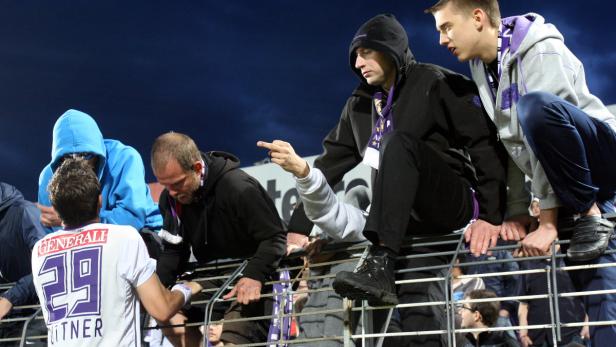 Ein Fußballspieler interagiert mit Fans hinter einer Absperrung.