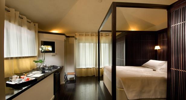 Ein Hotelzimmer mit Himmelbett, Schreibtisch und großem Fenster.