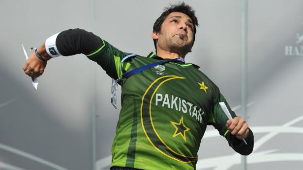 Ein Mann im pakistanischen Cricket-Trikot wirft Papierflugzeuge in die Luft.