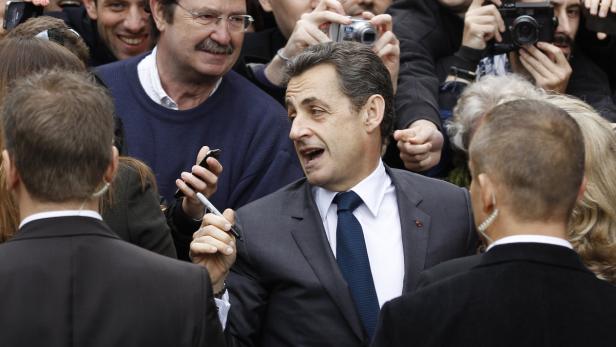 Nicolas Sarkozy umringt von Menschen, die Fotos machen und Autogramme wollen.