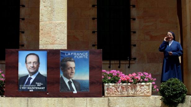 Eine Nonne telefoniert vor Wahlplakaten von François Hollande und Nicolas Sarkozy.