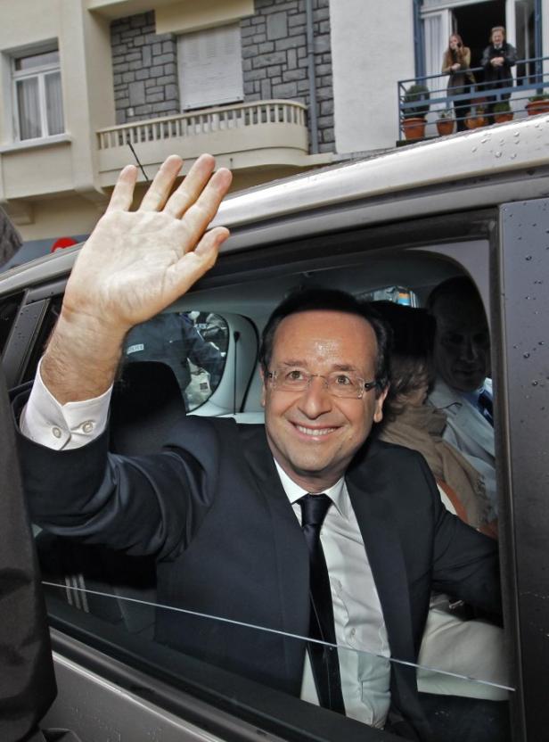 François Hollande winkt aus einem Auto heraus.