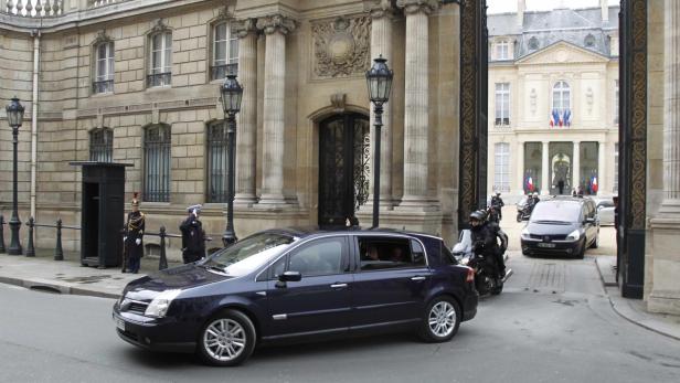 Ein dunkles Auto fährt vor dem Élysée-Palast in Paris vor.