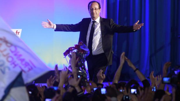 François Hollande steht auf einer Bühne und wird von jubelnden Menschen empfangen.
