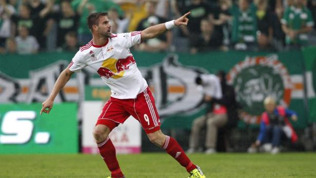 Ein Fußballspieler in rot-weißer Spielkleidung zeigt mit dem Finger nach oben.