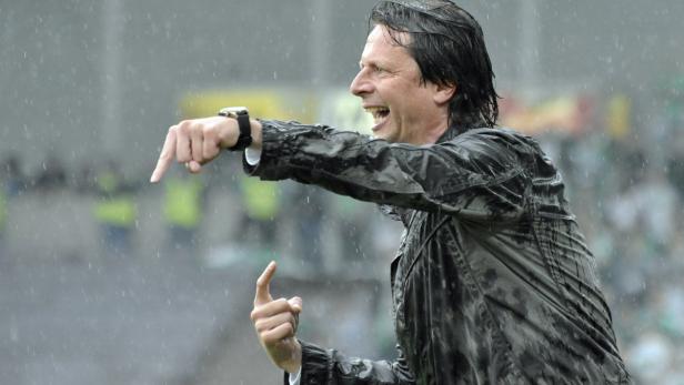 Ein Mann in Regenkleidung gestikuliert und scheint Anweisungen zu geben.