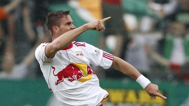 Ein Fußballspieler in einem weißen Trikot mit dem Red Bull Logo zeigt mit dem Finger.