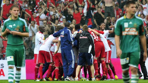 Fußballspieler feiern ein Tor vor einer jubelnden Zuschauermenge.