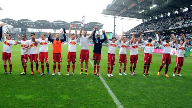 Eine Fußballmannschaft jubelt mit erhobenen Armen auf dem Rasen.