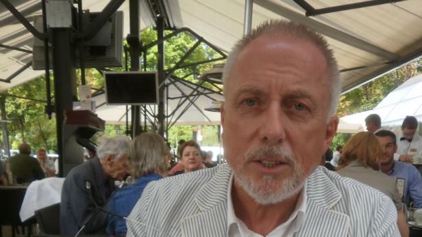 „Schnellschüsse aus dem Bauch sind keine Verkehrspolitik. Ich fordere eine Nachdenkpause.“ Prof. Ernst Pfleger, Ex-Gemeinderat. Ein Mann mit Bart sitzt in einem Straßencafé.