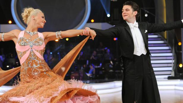 Ein Tanzpaar führt eine elegante Tanzbewegung auf einer Bühne aus.