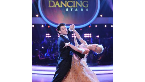 Ein Tanzpaar führt eine elegante Tanzfigur auf der Bühne von „Dancing Stars“ vor.