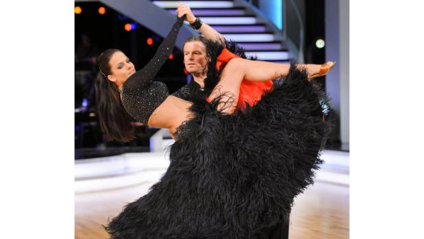 Ein Tanzpaar führt eine Hebefigur auf einer Bühne auf..