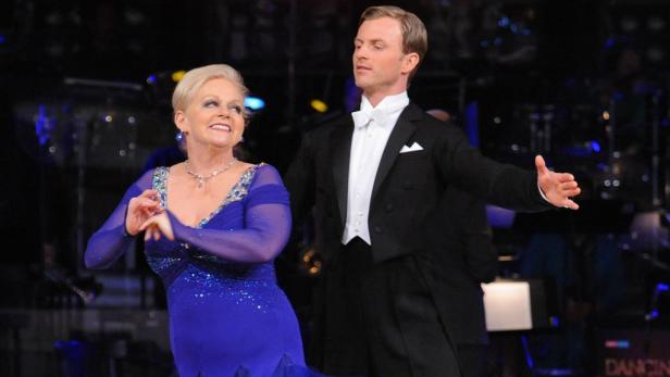 Eine Frau in einem blauen Kleid tanzt mit einem Mann im Smoking.