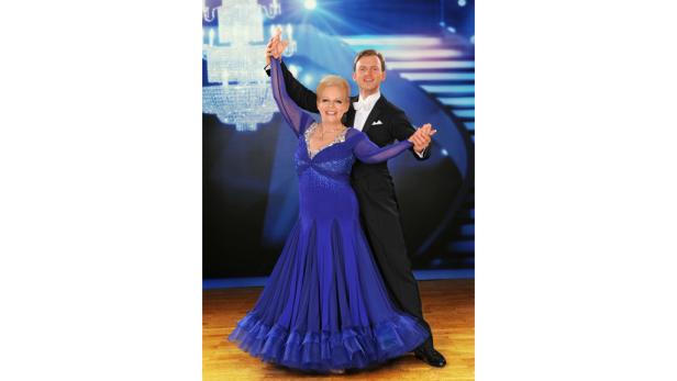 Ein Tanzpaar in festlicher Kleidung auf einer Bühne.