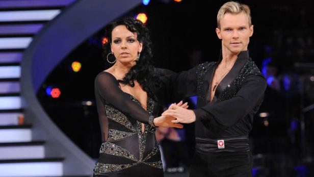 Ein Tanzpaar in glitzernden Kostümen auf einer Bühne.