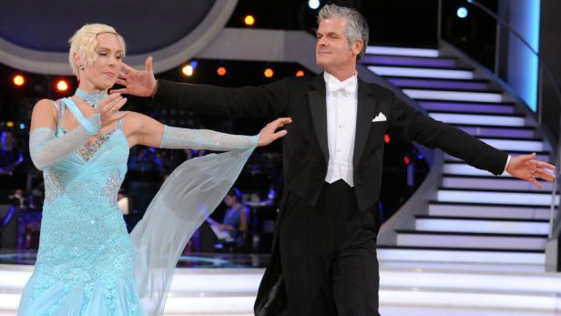 Ein Tanzpaar in festlicher Kleidung auf einer Bühne.