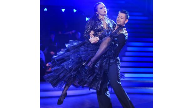 Ein Tanzpaar führt eine Hebefigur auf einer Bühne auf.